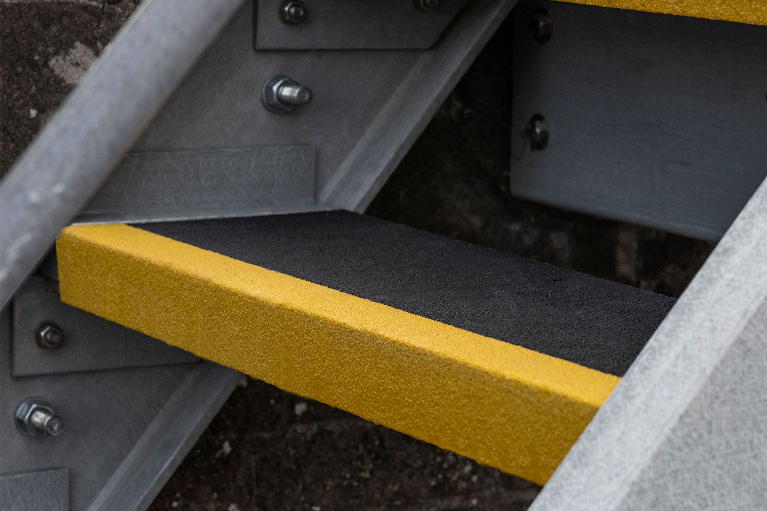 Close-up of a GRP anti-slip stair tread with high-visibility yellow nosing installed on a steel staircase, providing enhanced slip resistance and improved step edge visibility.