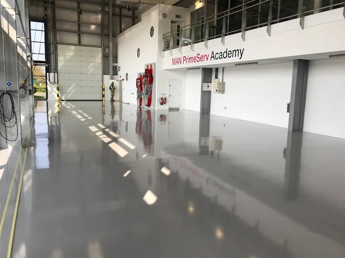 Large industrial or warehouse setting with epoxy resin painted floor and commercially branded sign.