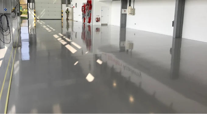 Large industrial or warehouse setting with epoxy resin painted floor and commercially branded sign.