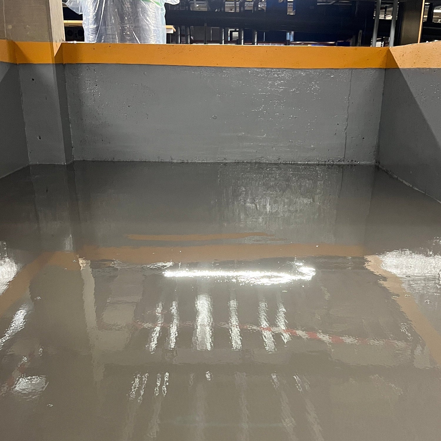Epoxy self-levelling industrial flooring with a smooth glossy grey finish applied in a commercial car park area