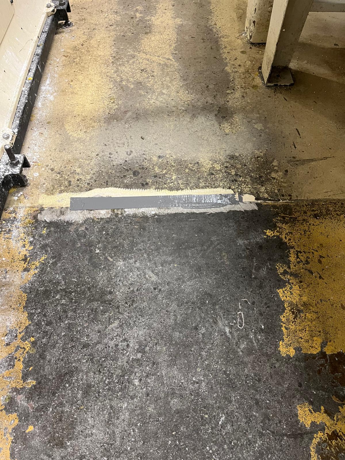 Grey expansion joint compound across an industrial floor